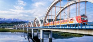 Local train crossing a river in Poland with mountains in the background
