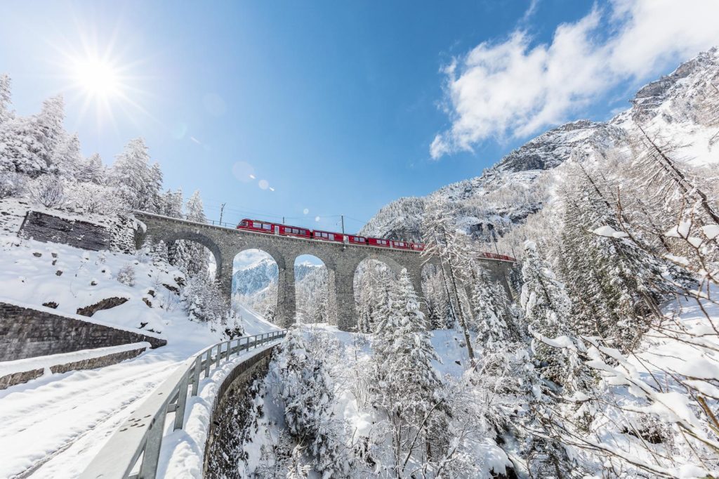 Train going through snowy mountains in winter in Switzerland