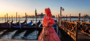 Figure in carnival costume in Venice at sunset during Venice Carnival
